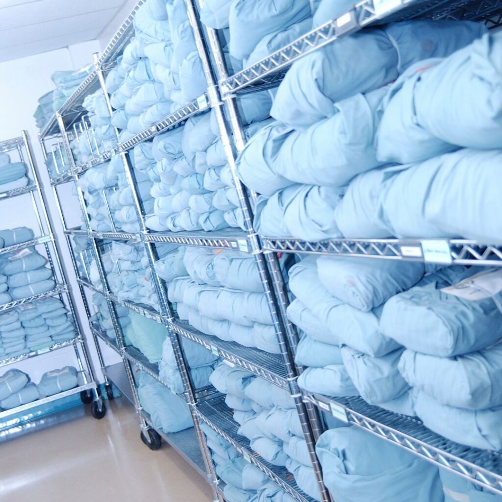 folded hospital linens on a metal shelf